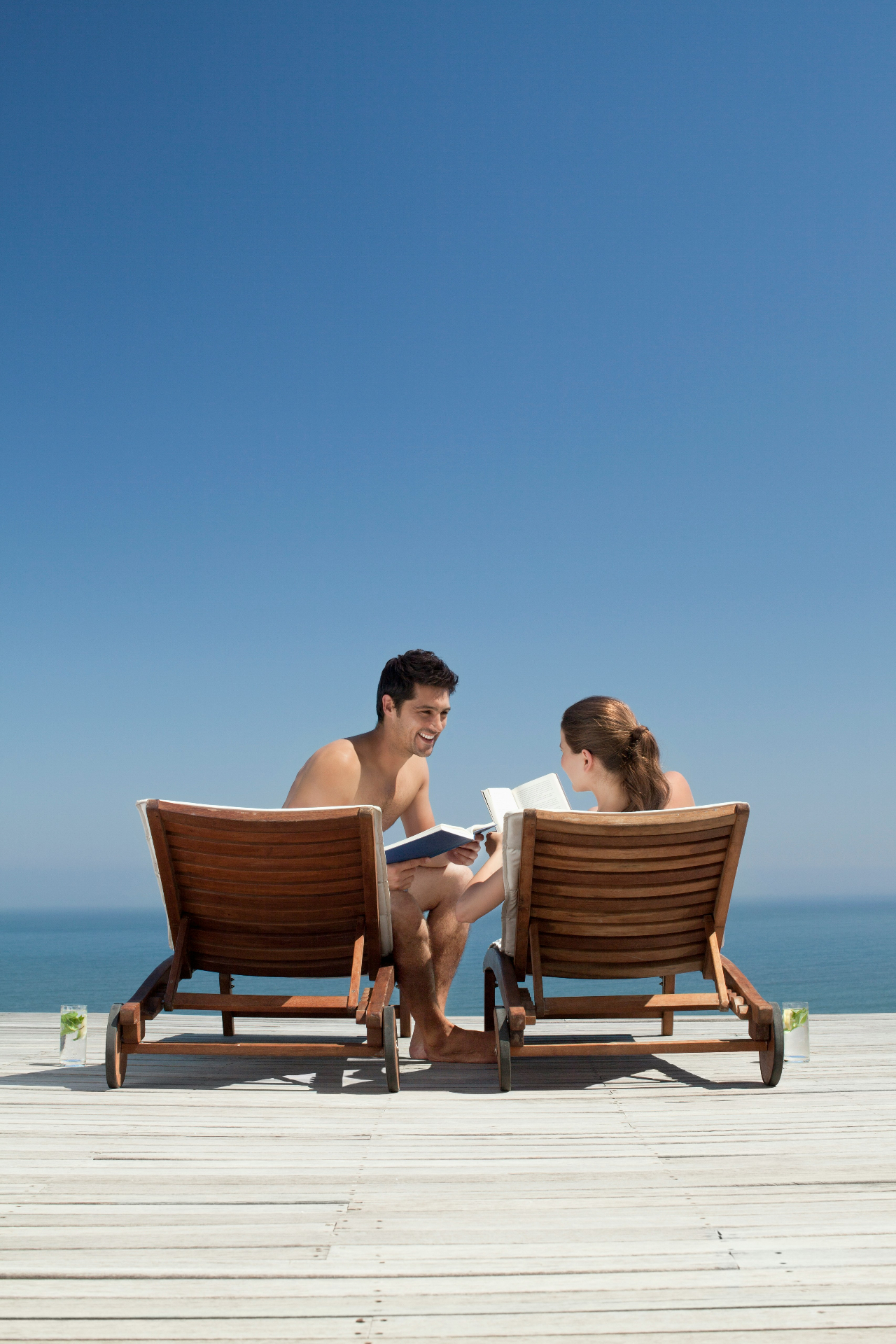 Couple relaxing on loungers by the sea
