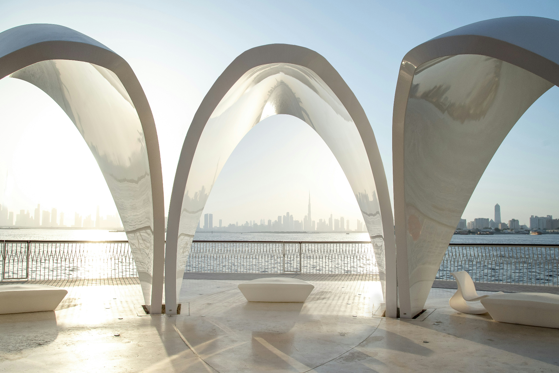 Modern white arches overlooking the Dubai skyline at sunrise